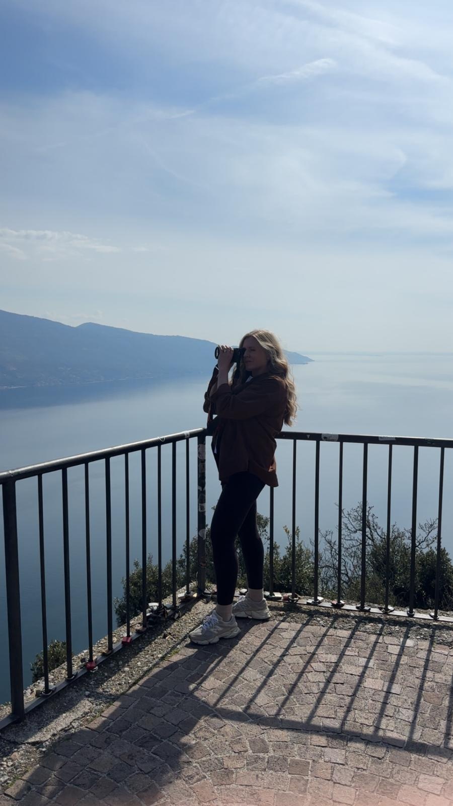 Terri Ellis photographing a lake and distant mountains from a scenic overlook.